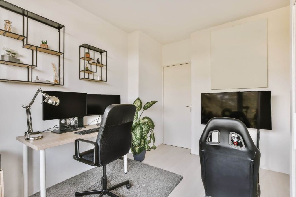 A home office with a desk, chair and tv.