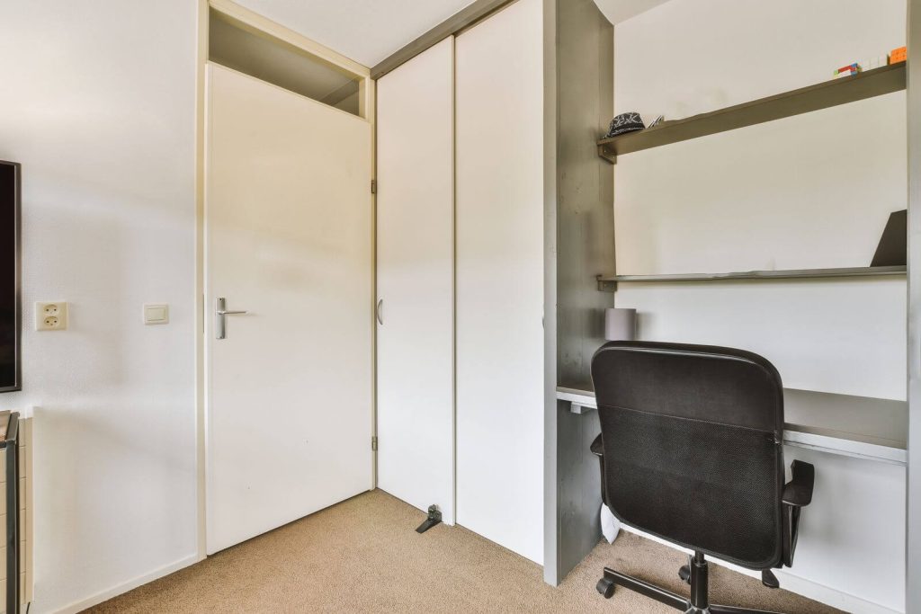 A room with a desk, chair and tv.