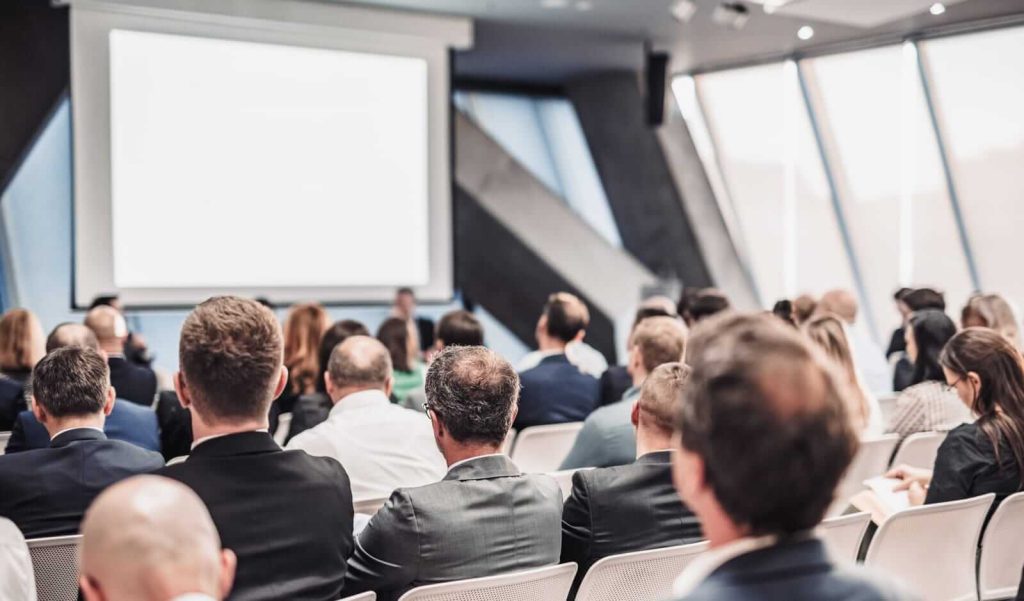 A group of people in a conference room watching a presentation.