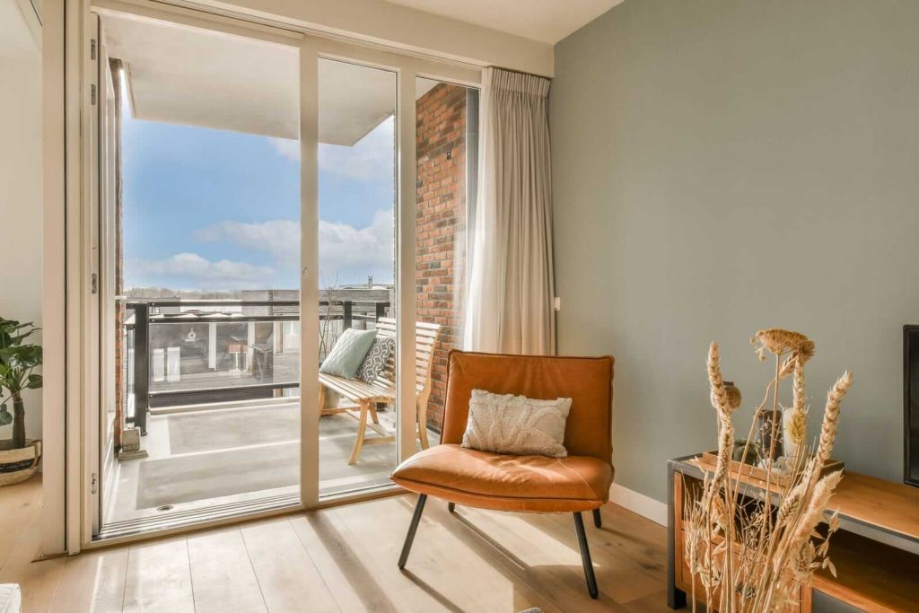 A living room with a balcony and a chair.