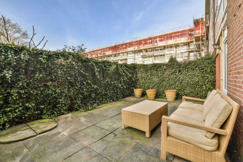 A patio with wicker furniture and a brick wall.