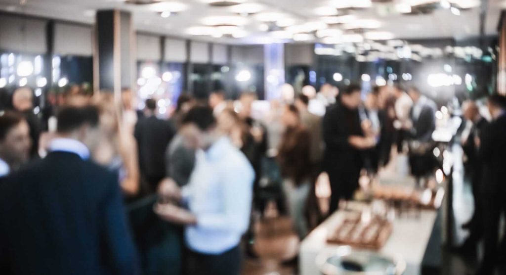 Blurred image of people gathered at an indoor event.