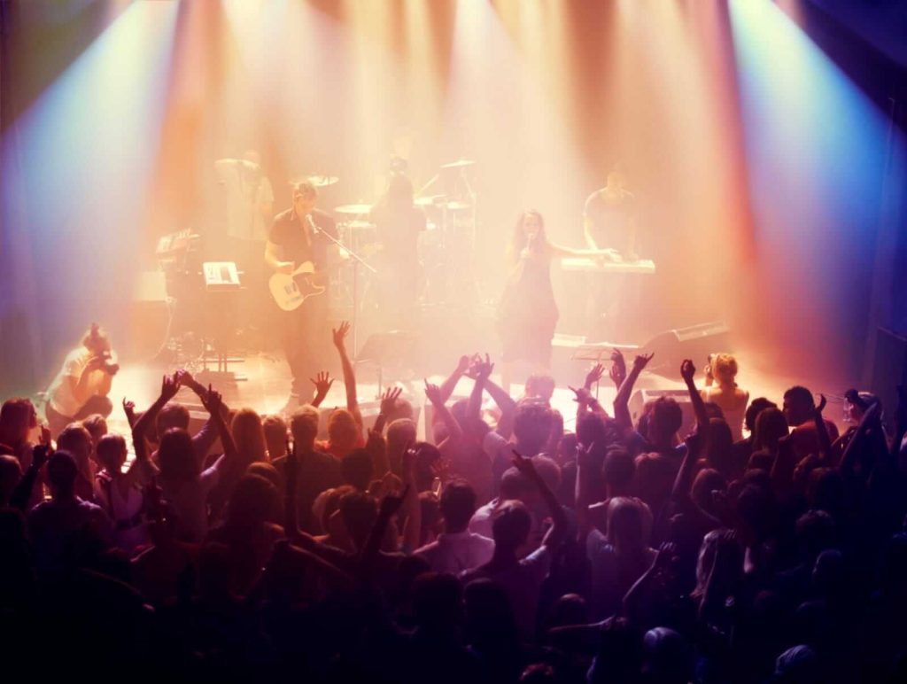 A vibrant concert scene with an energetic audience and a band performing on stage, bathed in colorful stage lights.