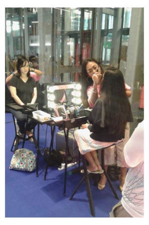 A woman is getting her makeup done at a Dressing Table.