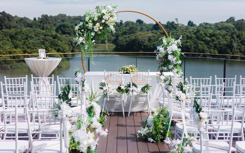 Outdoor wedding ceremony setup with premium floral arch and lake.