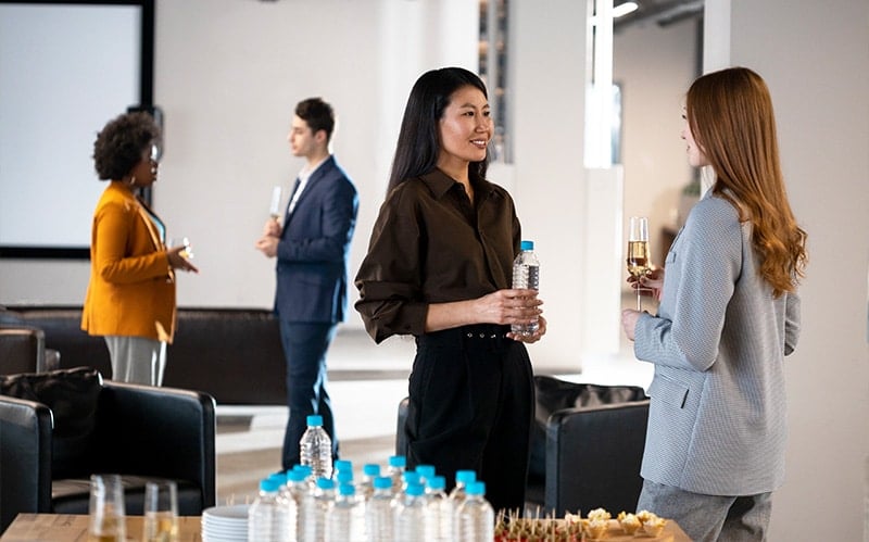 A group of professionals networking at a corporate event with refreshments