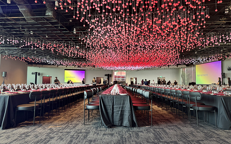 Banquet hall with black tables and pink lights.