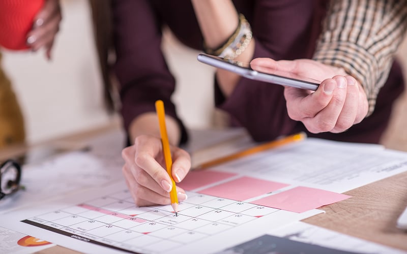 Marking dates on a calendar for exhibition furniture logistics planning.
